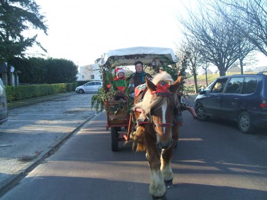    Pére Noël promené par un cob Normand avec un chariot western bâché.